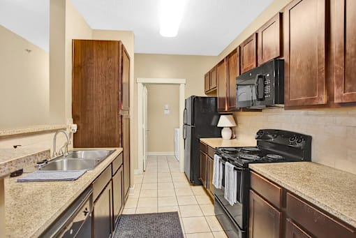 A kitchen with black appliances and wooden cabinets.