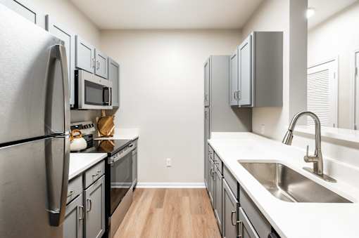 A kitchen with a refrigerator, microwave, oven, and sink.