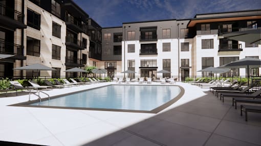 A swimming pool surrounded by lounge chairs and umbrellas in front of apartment buildings.