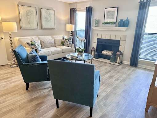 A living room with a white couch and a grey armchair at River Ridge Apartments in Asheville, NC