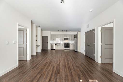 A spacious kitchen with white walls and a wooden floor.
