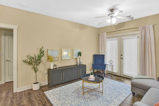 A living room with a blue rug and a ceiling fan.