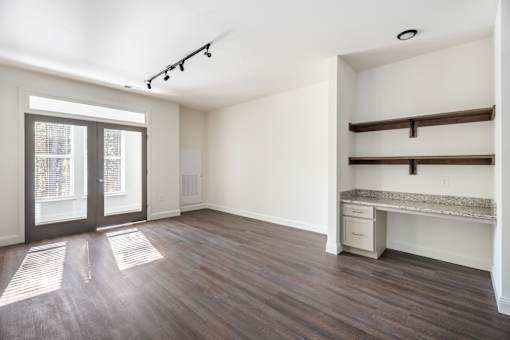 A room with a desk and a window with blinds.