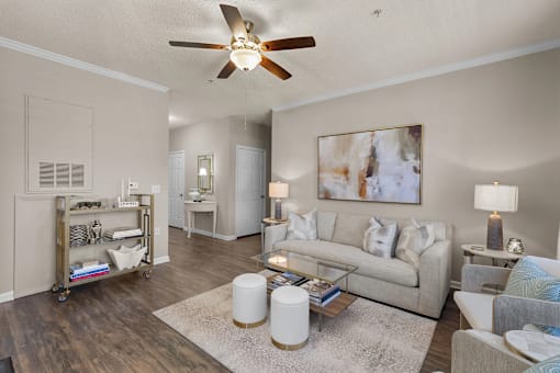 A living room with a white ceiling fan and a painting on the wall at Heights at New Garden apartments in Greensboro, NC.