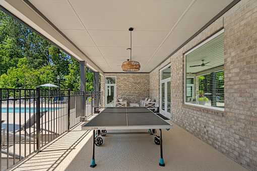 A ping pong table is in the middle of a covered patio.