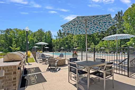 A poolside area with chairs, tables, and umbrellas.