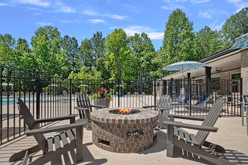 A fire pit sits in the middle of a patio surrounded by chairs.