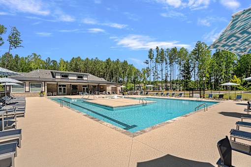 A large swimming pool surrounded by trees and a building.