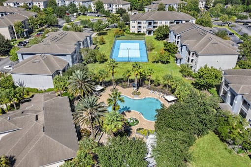 A bird's eye view of a residential area with a swimming pool surrounded by houses.