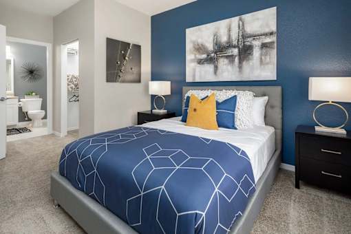 A bedroom with a large bed, pillows and a painting on the wall.