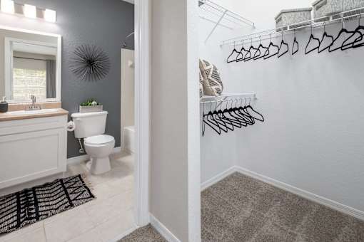 View with a bathroom with a toilet and sink plus the closet with hangers.
