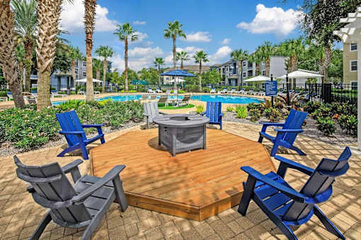 A poolside area with an outdoor firepit and five chairs surrounding.