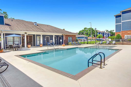 A swimming pool with a metal ladder and a building in the background.