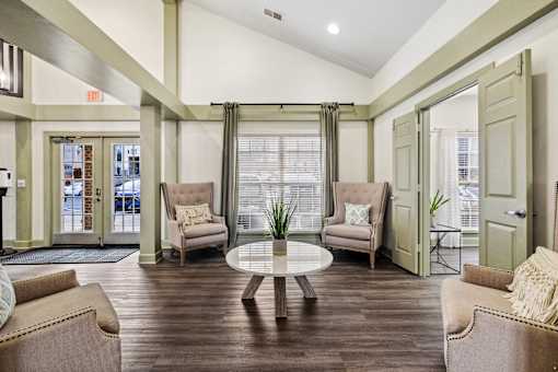 A living room with a brown couch, a white coffee table, and a window with curtains at Evergreen at the Bluffs apartments in Knoxville, TN.