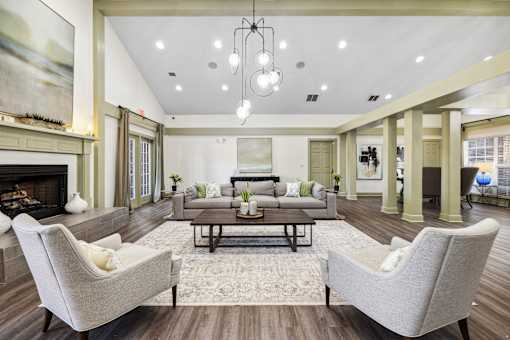 A seating area with a fireplace and two grey armchairs at Evergreen at the Bluffs apartments in Knoxville, TN..