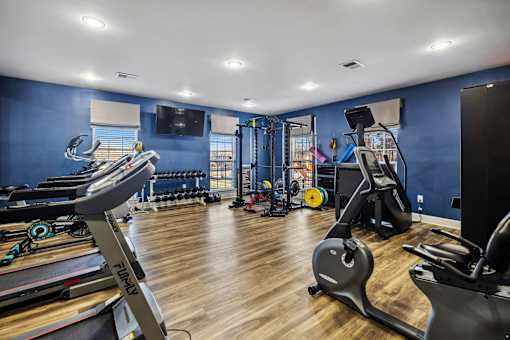 A gym with treadmills, elliptical machines, and other exercise equipment at Evergreen at the Bluffs apartments in Knoxville, TN..
