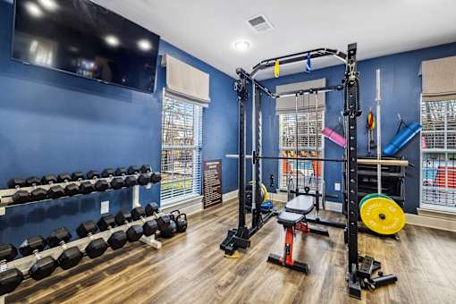 A gym with blue walls and a variety of equipment at Evergreen at the Bluffs apartments in Knoxville, TN..