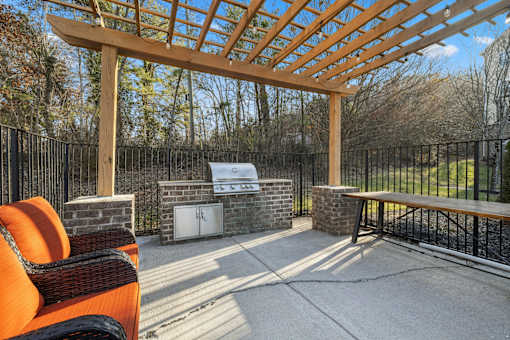 A patio with a wooden pergola and a black metal fence at Evergreen at the Bluffs apartments in Knoxville, TN..