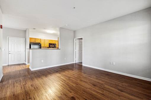 A large empty room with wooden floors and white walls at Evergreen at the Bluffs apartments in Knoxville, TN..