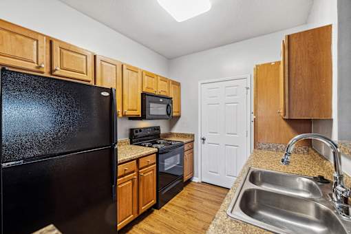 A kitchen with a black fridge, microwave, and stove at Evergreen at the Bluffs apartments in Knoxville, TN..