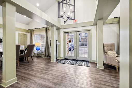 A well-lit foyer with a wooden floor and a large glass door at Evergreen at the Bluffs apartments in Knoxville, TN.