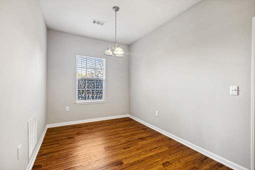 A room with wooden floors and a window with blinds.