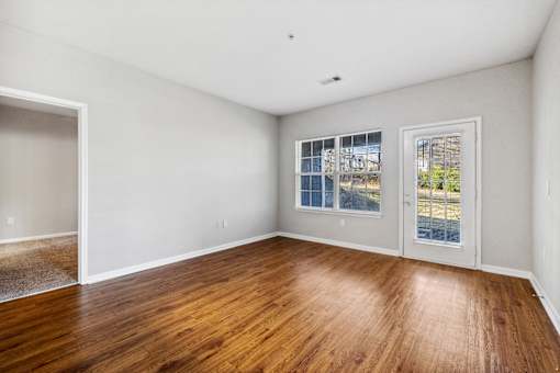 A room with wooden floors and a window overlooking a street at Evergreen at the Bluffs apartments in Knoxville, TN..