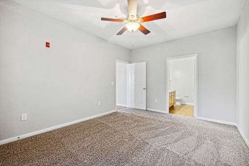 A room with a ceiling fan and carpeted floor.