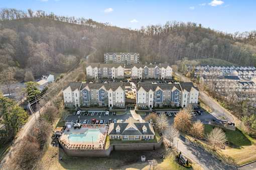 A large apartment complex with a swimming pool in the foreground at Evergreen at the Bluffs apartments in Knoxville, TN..