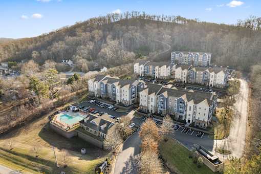 An aerial view of apartment buildings with a pool in the foreground at Evergreen at the Bluffs apartments in Knoxville, TN..