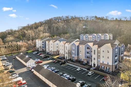 A large apartment complex with a parking lot in front at Evergreen at the Bluffs apartments in Knoxville, TN..