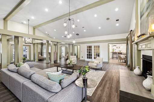 A large, well-lit clubhouse with a grey sofa and wooden floors at Evergreen at the Bluffs apartments in Knoxville, TN..