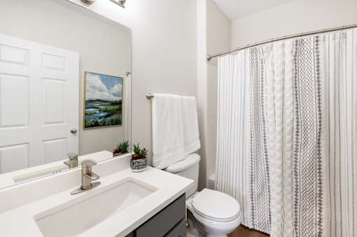 A white bathroom with a toilet, sink, and shower curtain.