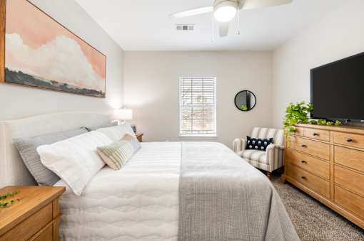 A bedroom with a large bed, a chair, and a painting on the wall.