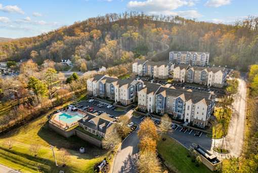 An aerial view of apartment buildings with a pool in the foreground.