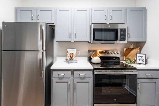 A modern kitchen with a stainless steel refrigerator and a black stove top.