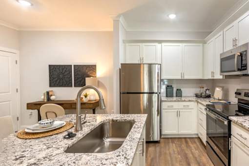 A modern kitchen with a granite countertop and stainless steel appliances.