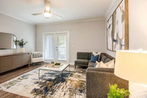 A living room with a rug, a couch, a chair, a table, and a painting on the wall.