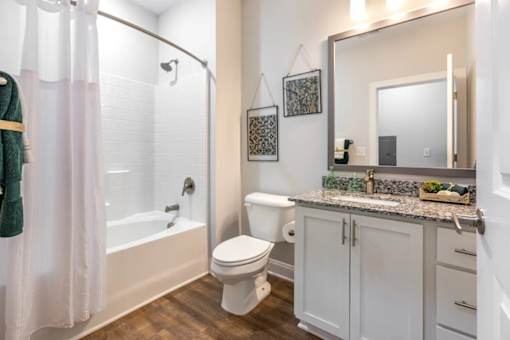 A white toilet sits in a bathroom next to a sink and a bathtub.