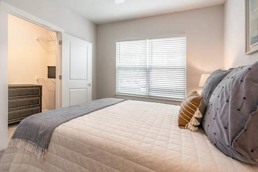 A bedroom with a bed, pillows, and a blanket.