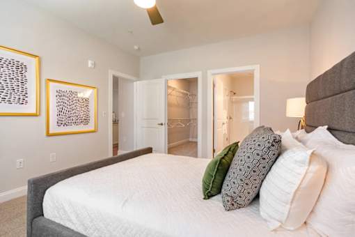 A bedroom with a bed, two pillows, and two framed pictures on the wall.