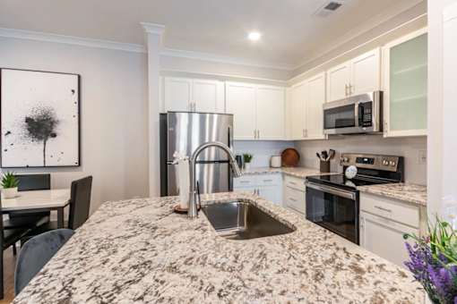 A kitchen with a granite countertop and stainless steel appliances.