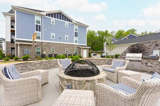 A patio with a fire pit and chairs.