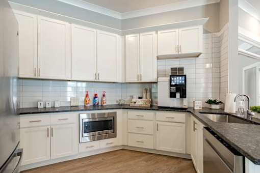 A kitchen with white cabinets and a black countertop.