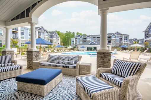 A patio with striped chairs and a pool in the background.