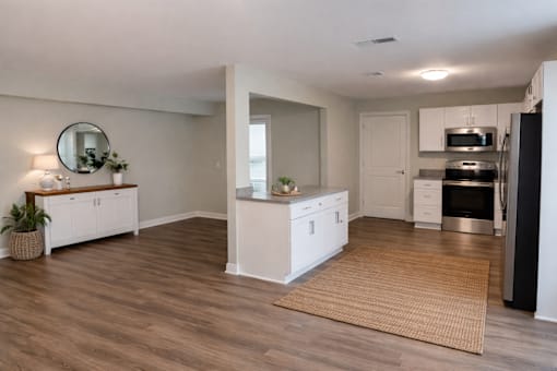 A modern kitchen with white cabinets and a wooden floor.