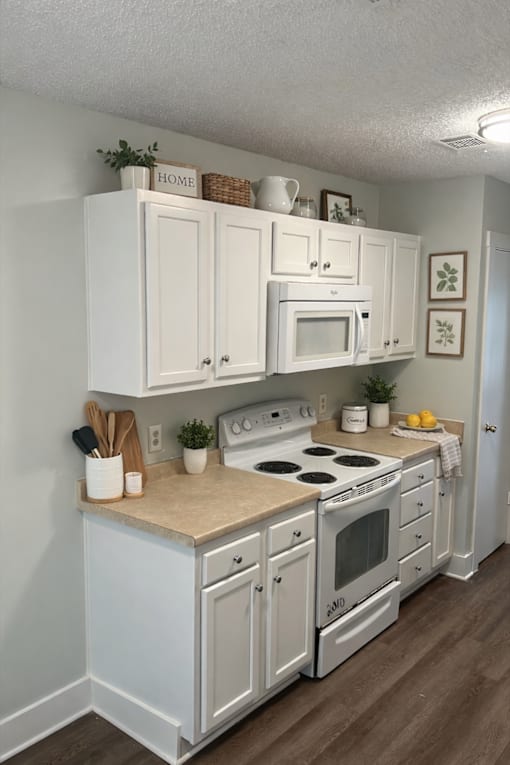A white kitchen with a stove, oven, and microwave.