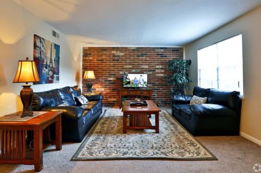 a living room with leather furniture and a brick wall