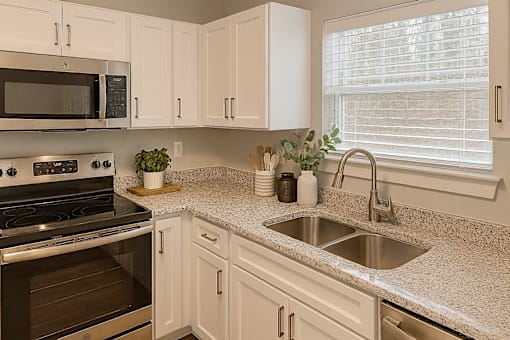 A kitchen with a stove, microwave, and sink.