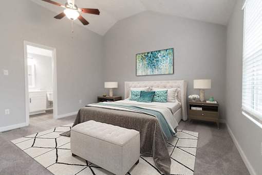A bedroom with a bed, a bench, and a ceiling fan.